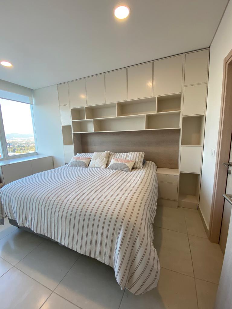 Mueble a medida con cabecera y clóset empotrado en recámara moderna con vista panorámica.