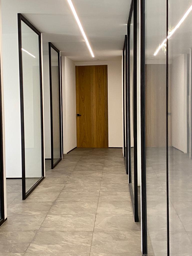 Pasillo con divisiones de cristal y puerta de madera en oficina jurídica – diseño interior Barniture