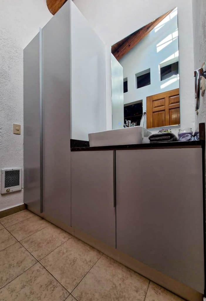 Mueble de baño a medida en acabado gris mate con espejo grande y almacenamiento oculto, diseñado por Barniture.